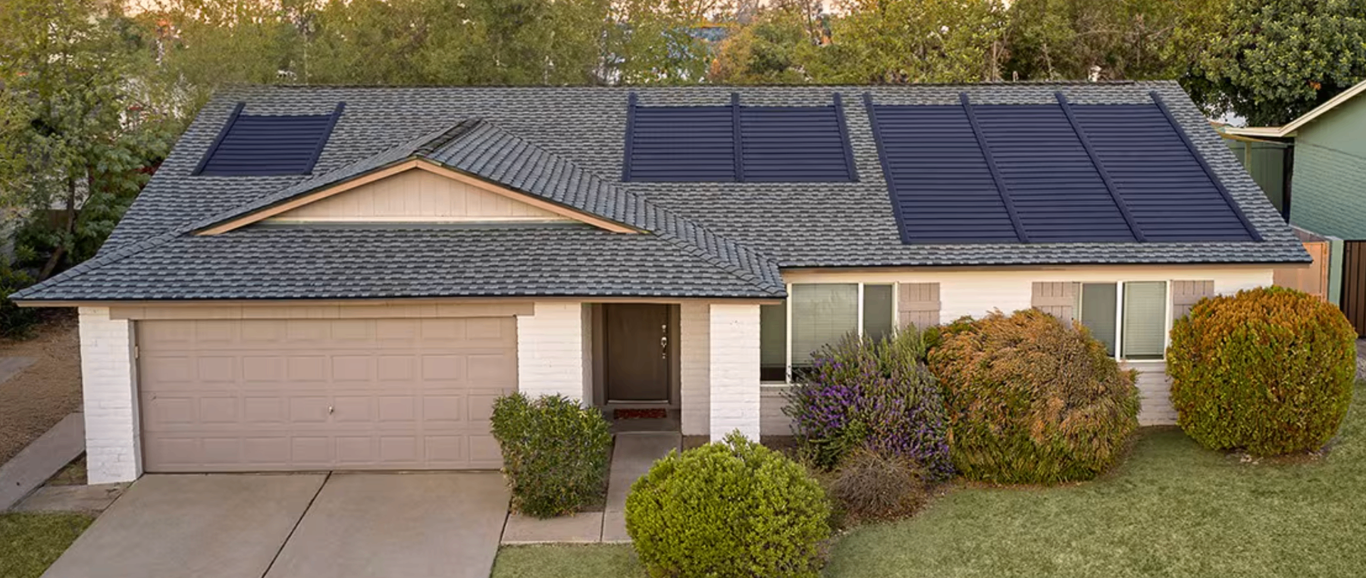 Suburban home with an integrated GAF Energy Shingle solar roof at golden hour